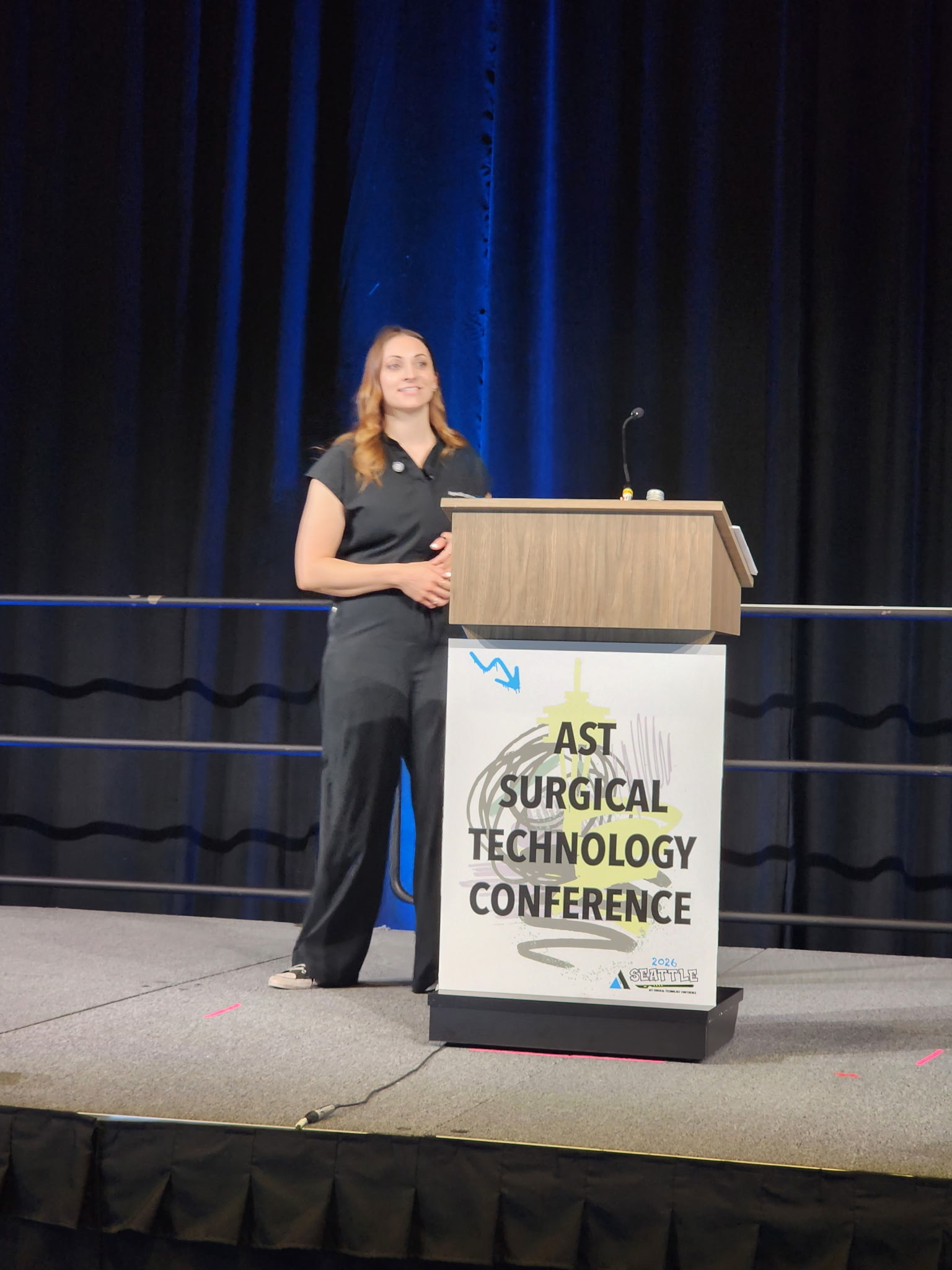 Alyssa Ellis speaking on stage at a surgical technology conference